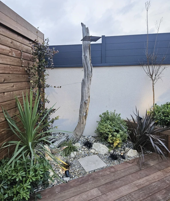 Jardin paysager extérieur avec sculpture en bois flotté central, aménagement contemporain sur terrasse