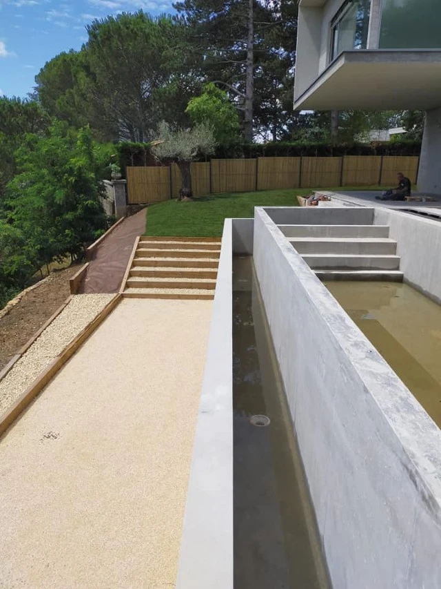 Jardin contemporain extérieur avec terrasse en bois composite, sculpture décorative en bois flotté sur lit de galets