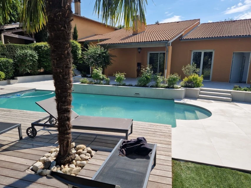 Jardin contemporain extérieur avec terrasse en bois composite, sculpture décorative en bois flotté sur lit de galets