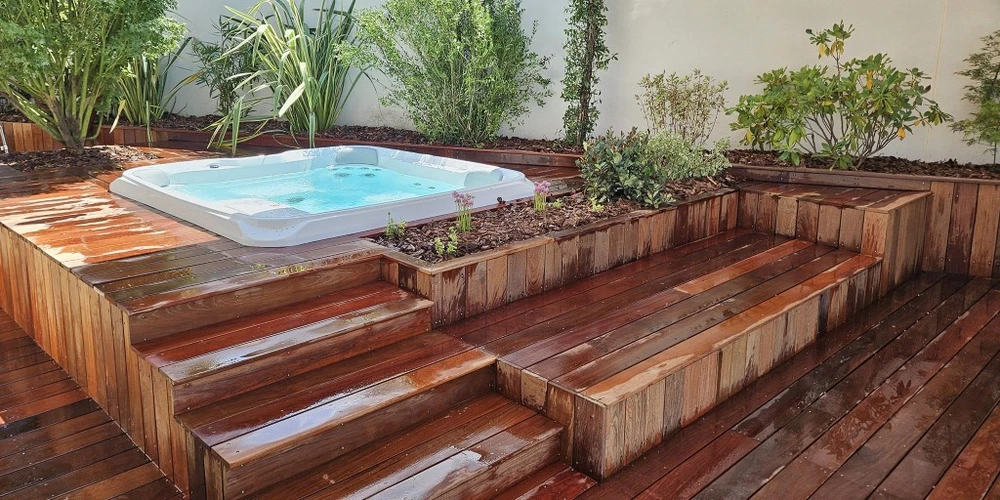 Jardin contemporain extérieur avec terrasse en bois composite, sculpture décorative en bois flotté sur lit de galets