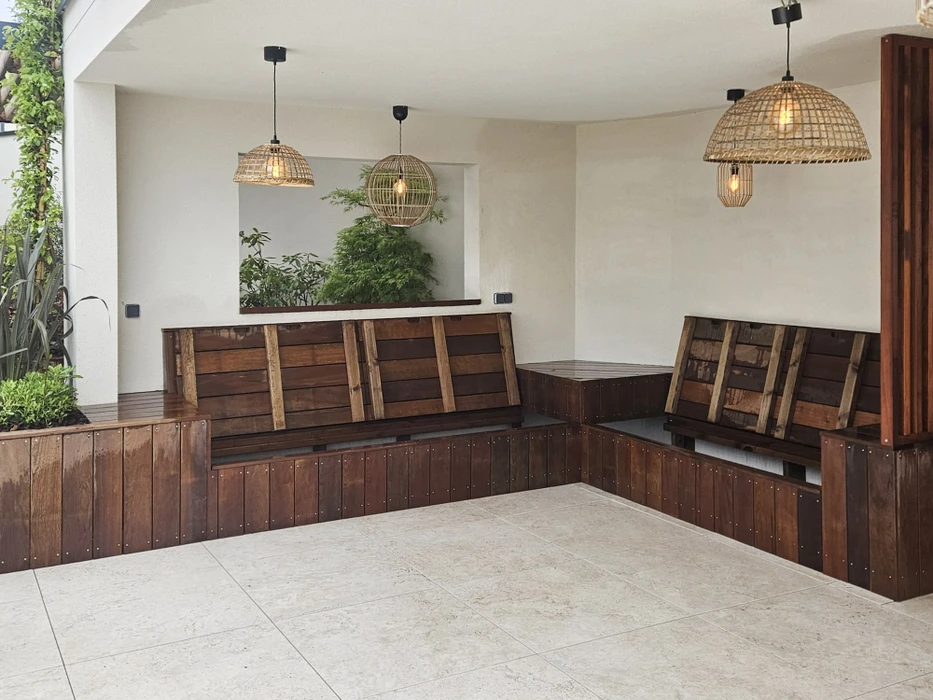 Terrasse extérieure en bois avec pergola, mobilier de jardin et végétation luxuriante