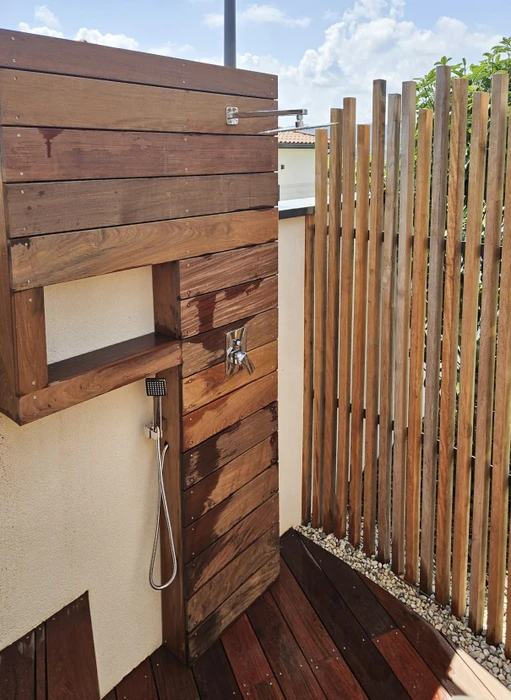Terrasse extérieure moderne avec deck en bois exotique, personne utilisant barbecue sous pergola bois